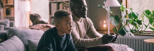 Father and son on sofa playing video game